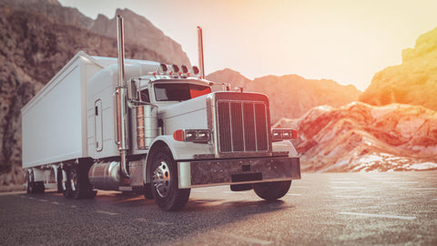 White big rig on road in early morning mountain sunrise.