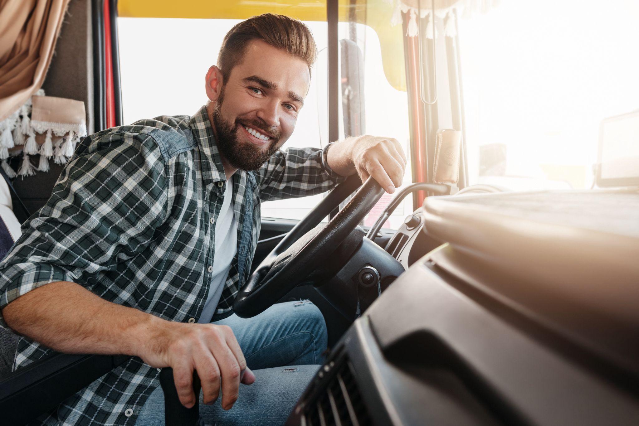 Young and happy smiling truck driver inside his vehicle