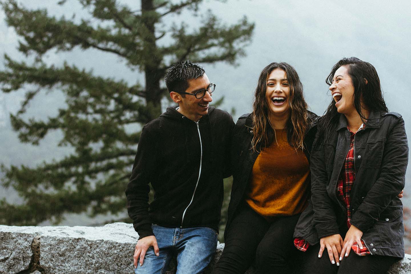 Three people sitting on a rock wall