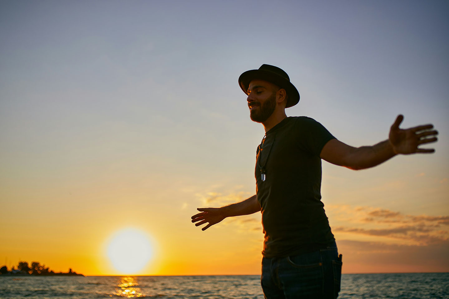 Man standing by the water at sunset