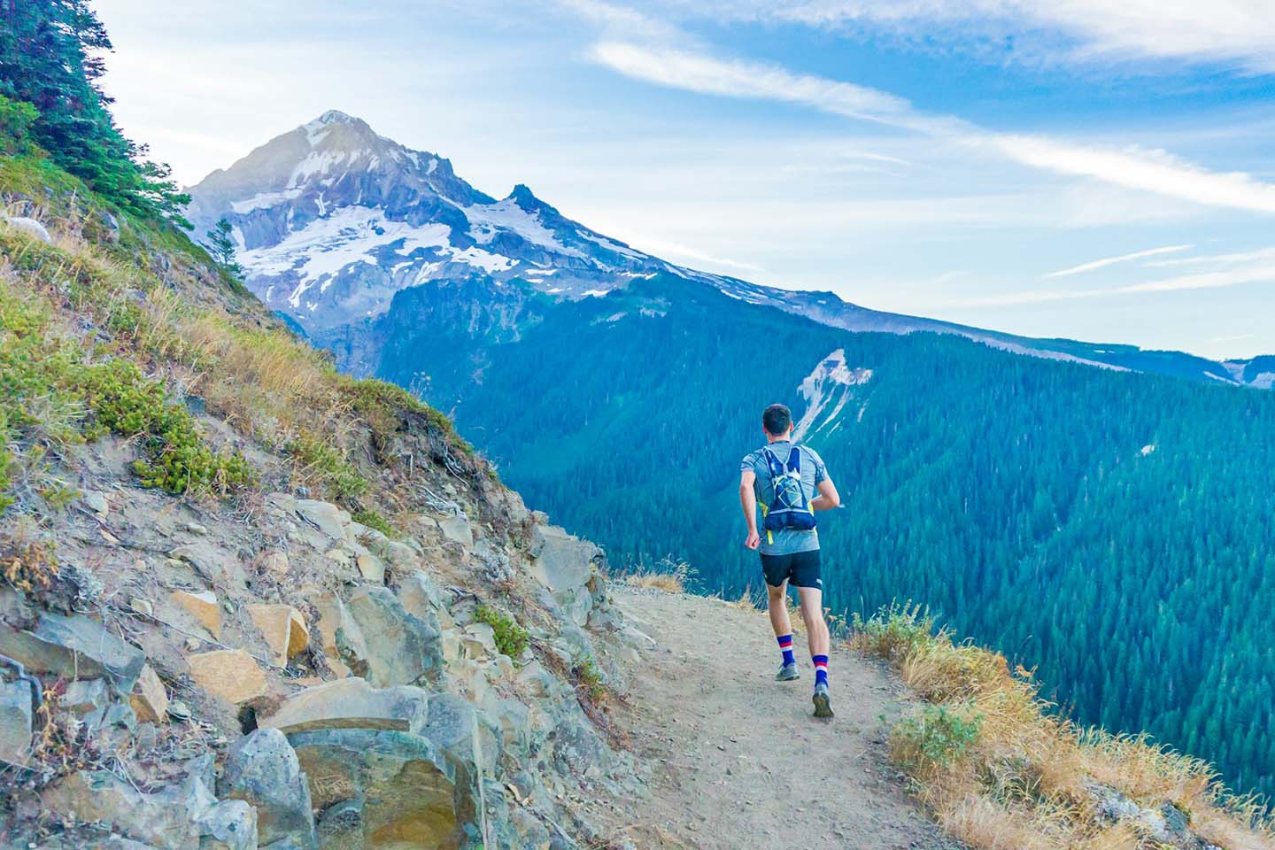 a man running near edge of mountain overlooking trees