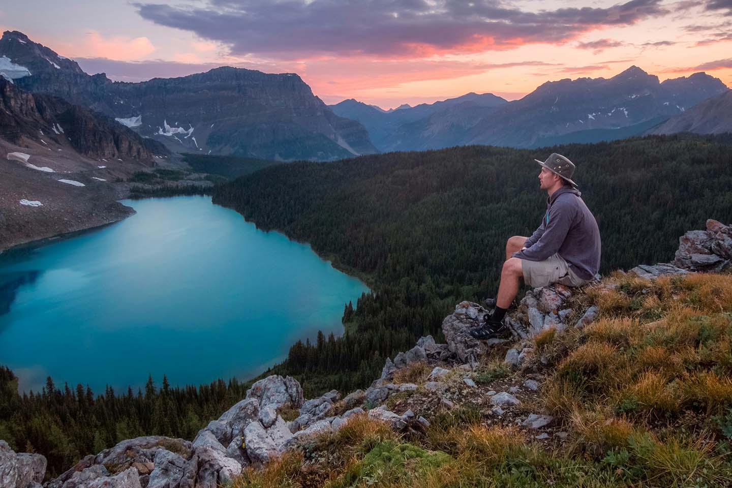 man looking on mountain sitting on rock