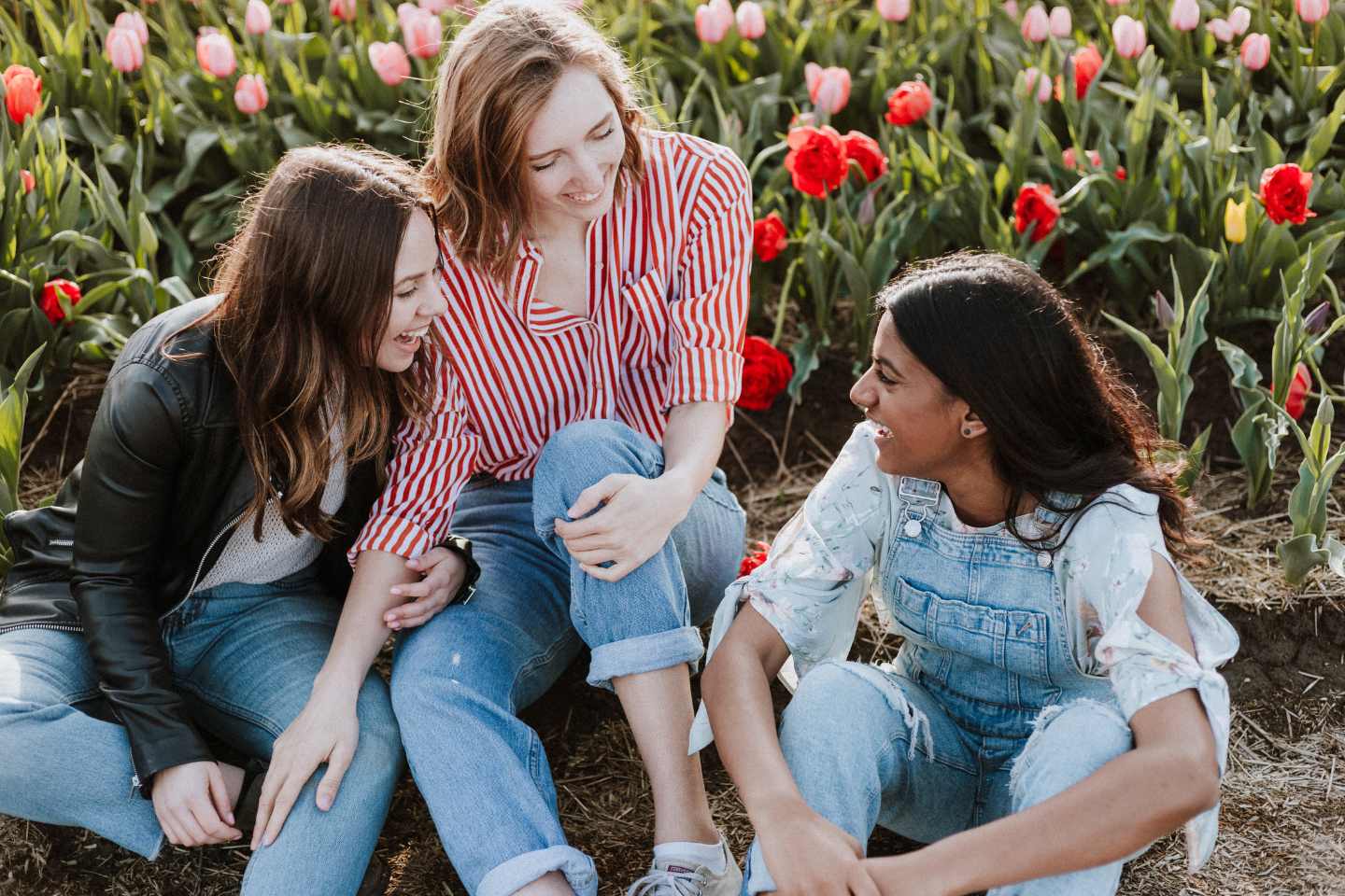 three women sitting in a field of colorful tulips