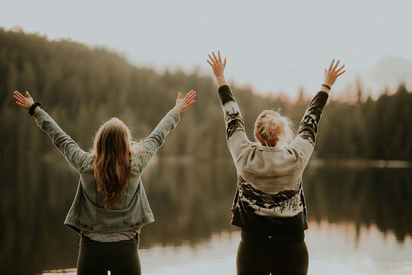 two women raising their hands together