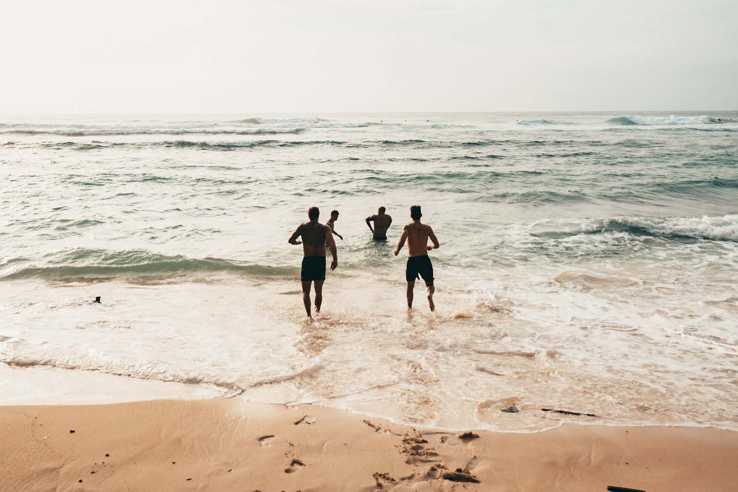 group of friends running towards the beach