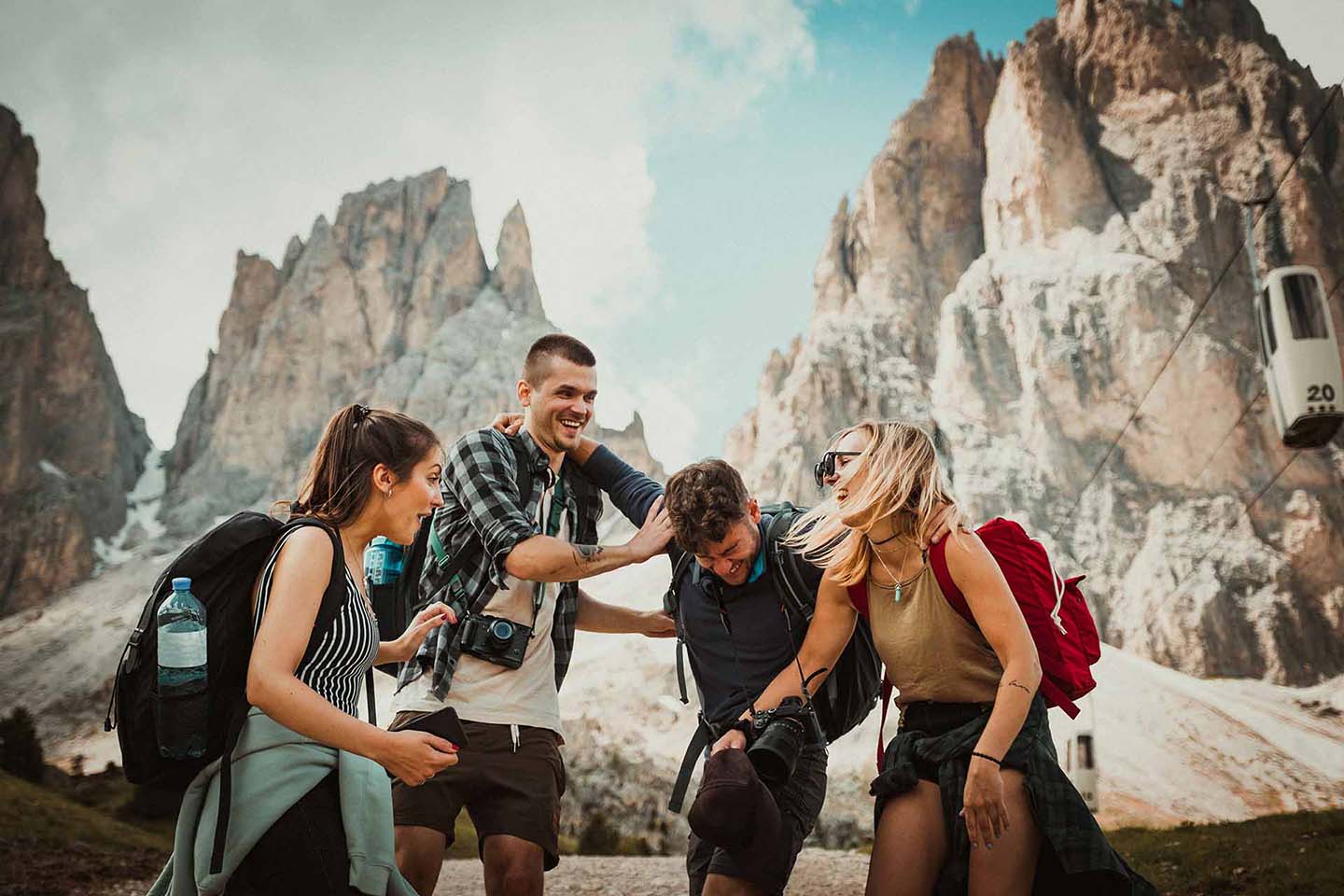 Group of friends laugh together in front of a large mountain range.