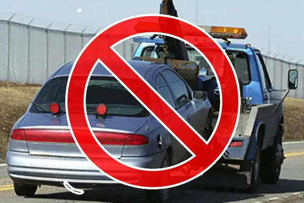 Car being towed with a prohibition symbol overlay.