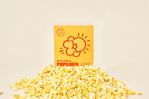 A box of Popsmith's Oh Sooo Buttery Popcorn on top of a pile of popcorn