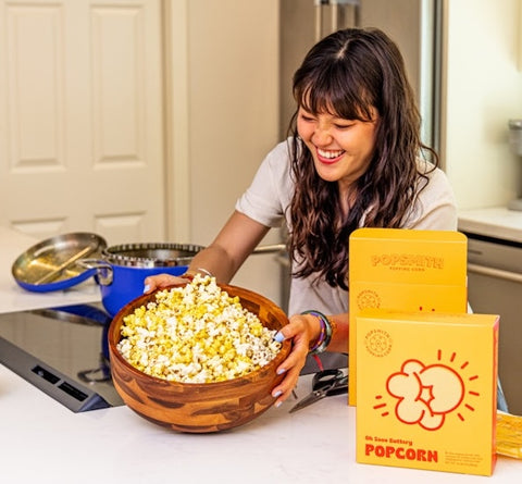 girl grins while showing off bowl of popcorn