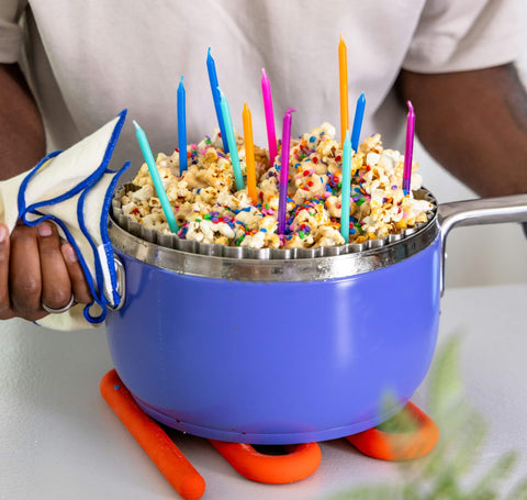 man holds a cobalt popper filled with birthday cake flavored popcorn