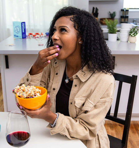 woman tries popcorn while holding a small bowl