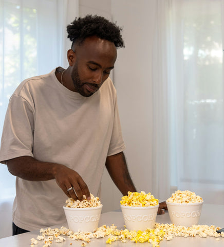 Man takes a handful of popcorn from a bowl