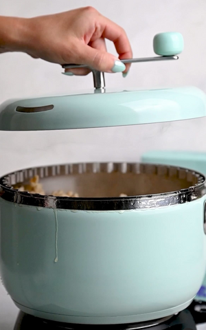 Person puts the Popper's lid back on the pot