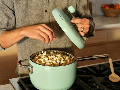 Man removes lid of Popper to reveal freshly popped popcorn