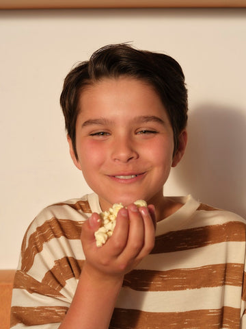 Young boy smiles while holding popcorn