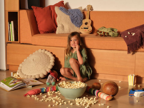 Little girl eats popcorn while sitting on the floor