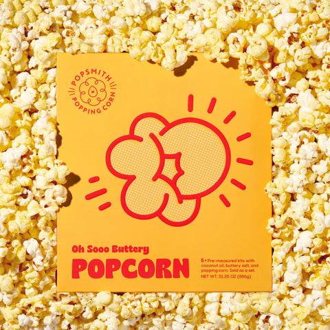 A box of Popsmith Oh Sooo Buttery Popcorn surrounded by popcorn