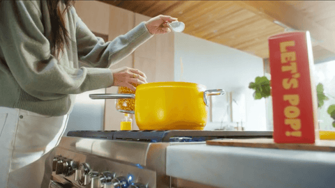 Woman pours kernels into a yellow Popsmith popcorn popper