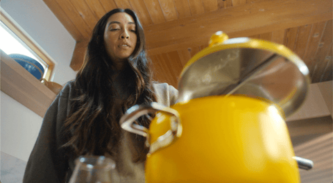 Woman removes the lid of a yellow popcorn popper
