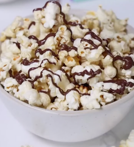 closeup of chocolate drizzled popcorn in a bowl