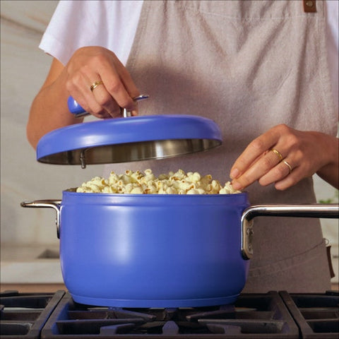 woman opens lid of popcorn popper to reveal cooked popcorn