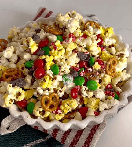 Butter popcorn with M&Ms, pretzels, chocolate chips, sprinkles and melted white chocolate