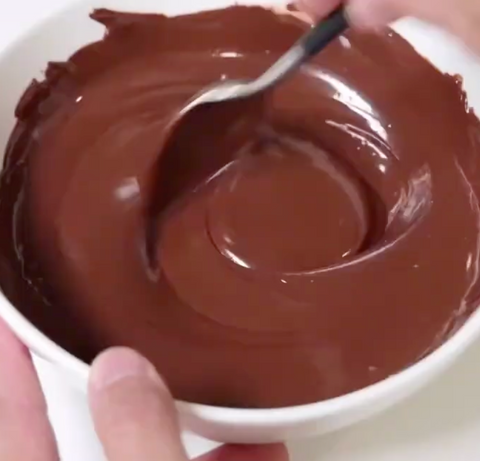 person stirs melted chocolate chips in a bowl
