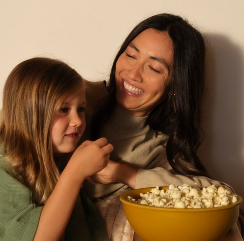 mom and daughter smile while eating popcorn