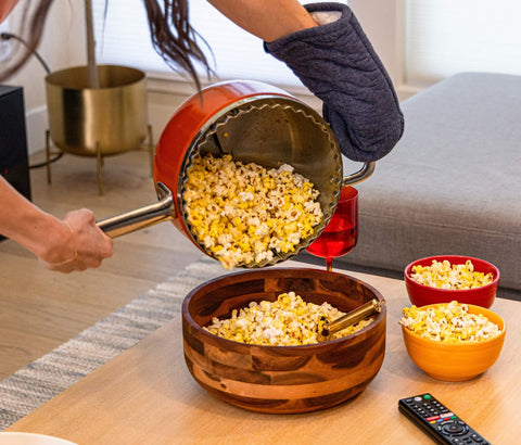 Woman pours popcorn from Popper into a wooden bowl