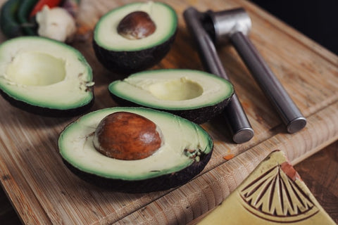 two sliced avocado on a wooden chopping board