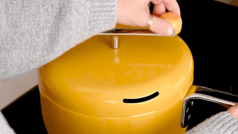 Woman turns crank of stovetop popcorn popper