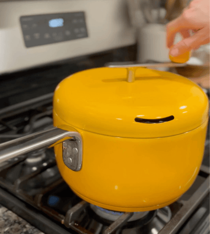 woman turns crank of yellow popcorn popper to make cajun popcorn