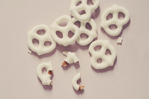 white chocolate coated pretzels on a beige surface