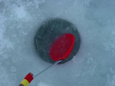 Clearing the ice fishing hole with a homemade ice scooper Stock