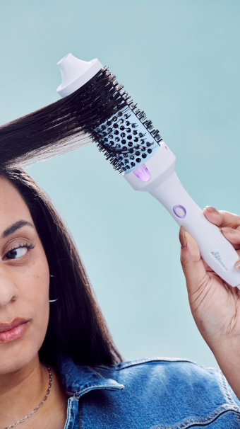 Person using the It’s Giving Body Large Hot Round Brush 1.77" (45MM) in a strand of dark brown hair