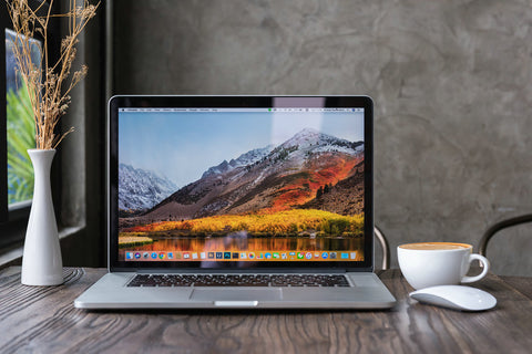 Macbook pro computer with dried flower vase and latte art coffee on wooden table