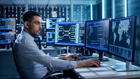 System security experts who work in system control centers. The room is filled with screens displaying all kinds of information.