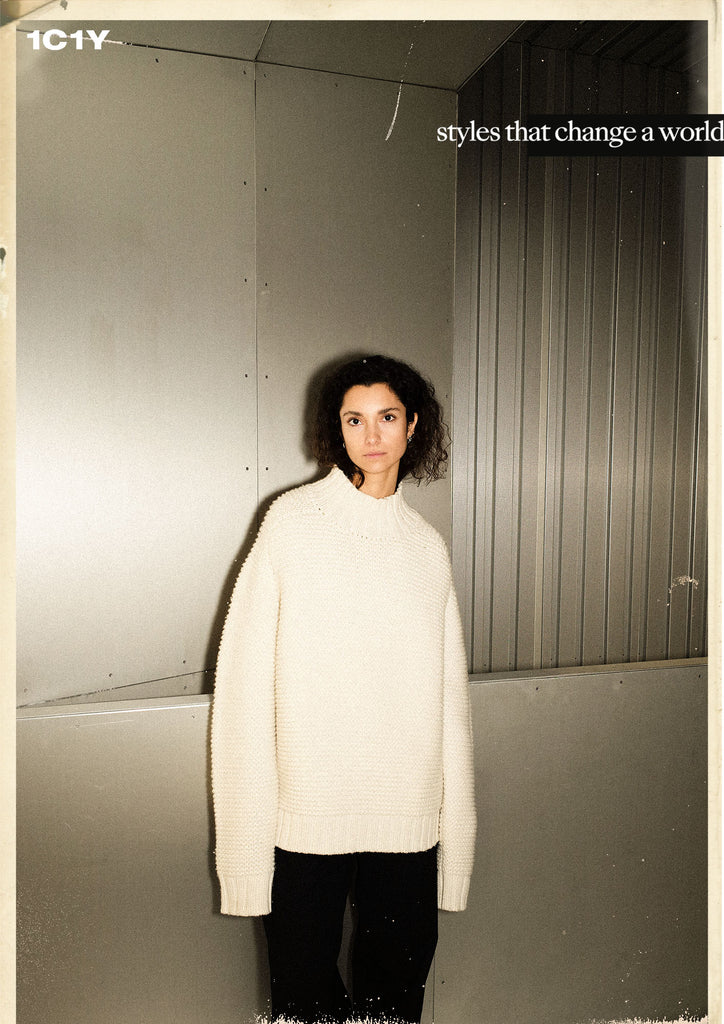 cover picture of model in big ivory knit in front of shiny wall