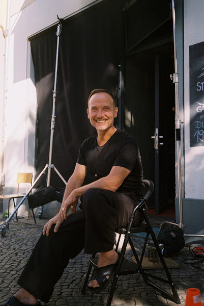 bernd keller sitting on chair smiling looking at camera dressed in black 1c1y