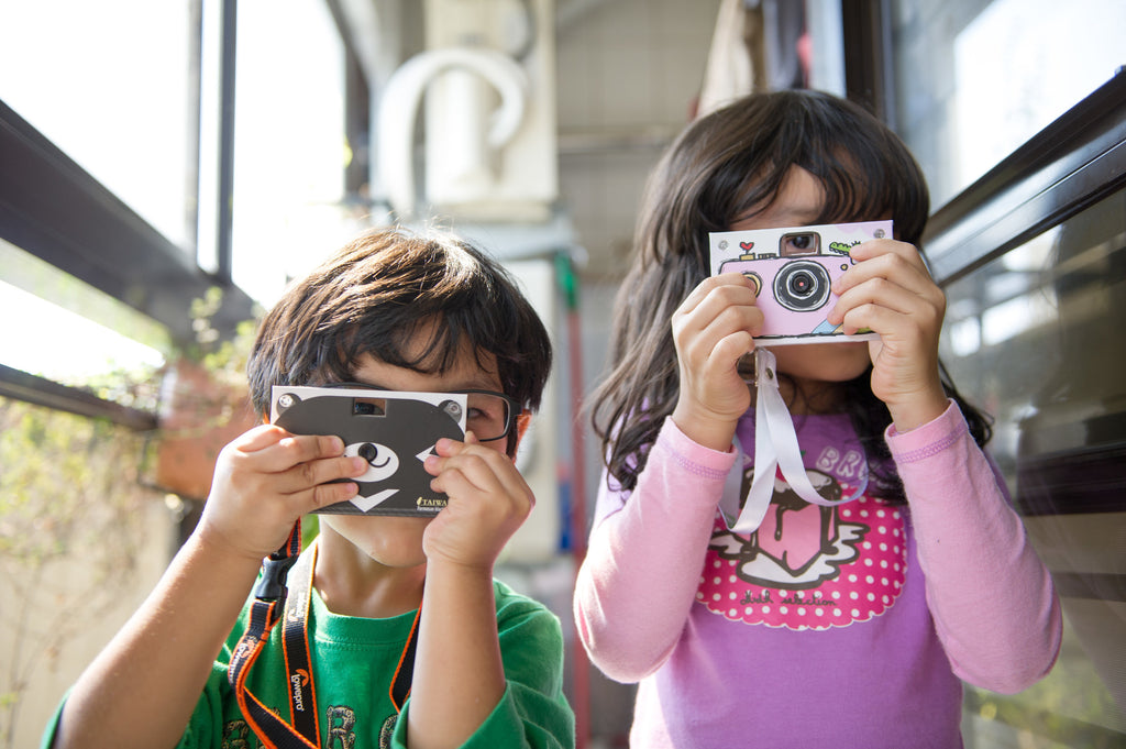 Kids taking photos with paper shoot cameras