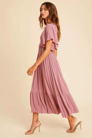  A model wears a pink maxi dress with heels. 