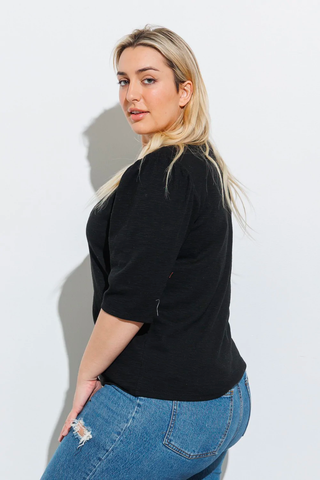 A woman in a flattering black top and jeans. 