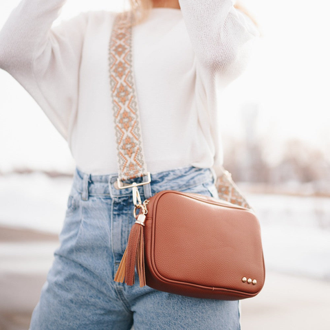 a woman wearing a camel-colored crossbody bag