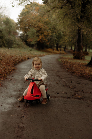 Girl riding Didicar through woodland
