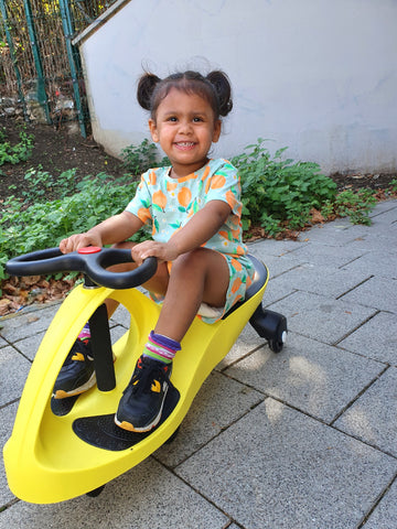 Girl riding a yellow Didicar ride on toy