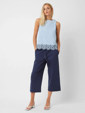 Model wearing sleeveless light blue top and navy cropped trousers. 