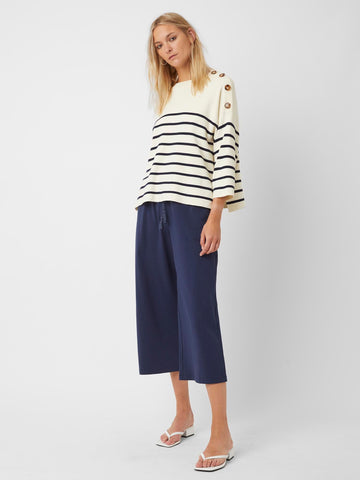 Model wearing navy and cream sweater and navy cropped trousers.
