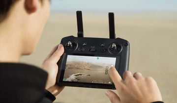 A person operating a remote controller with a built-in display, DJI RC PRO.