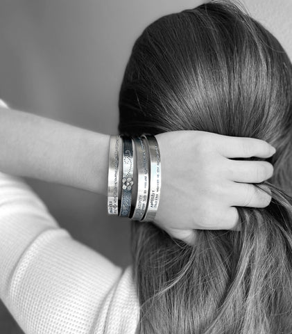 stack of silver cuff bangles on a model