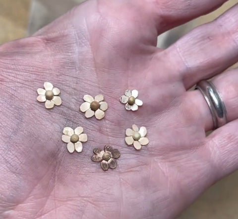 Bench jewelers hand with tiny flower details for rings